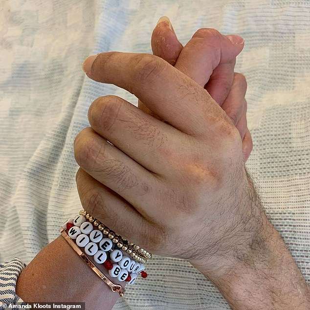 Be strong: She finished her caption with a strong message, saying: 'This virus is a real thing and needs to be taken seriously and stopped. We will always do what we can to support that.' Above is a photo of Amanda holding Nick's hand