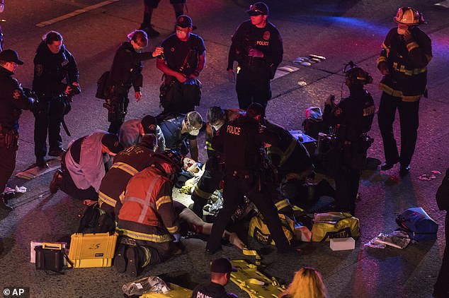 Emergency workers tend to an injured person on the ground after a driver sped through a protest-related closure on the Interstate 5 freeway in Seattle