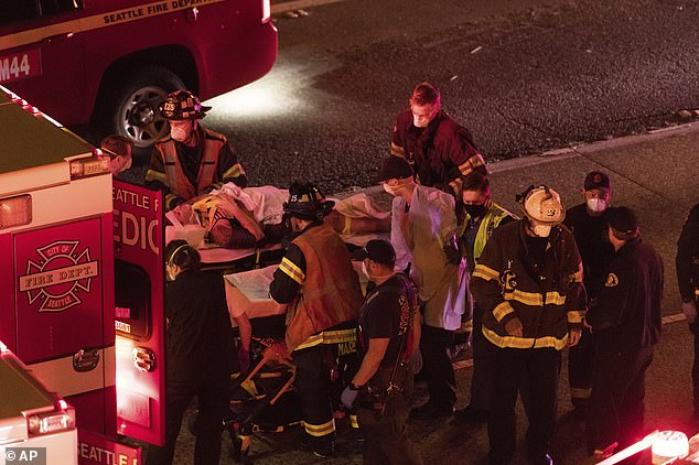 Love and fellow protester, Diaz Love, are pictured being put into an ambulances by first responders after they were hit by a speeding car on Interstate 5