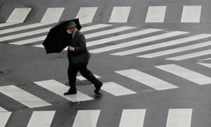 A man wearing a protective mask makes his way through rain amid the coronavirus outbreak in Tokyo, Japan, 19 May 2020.