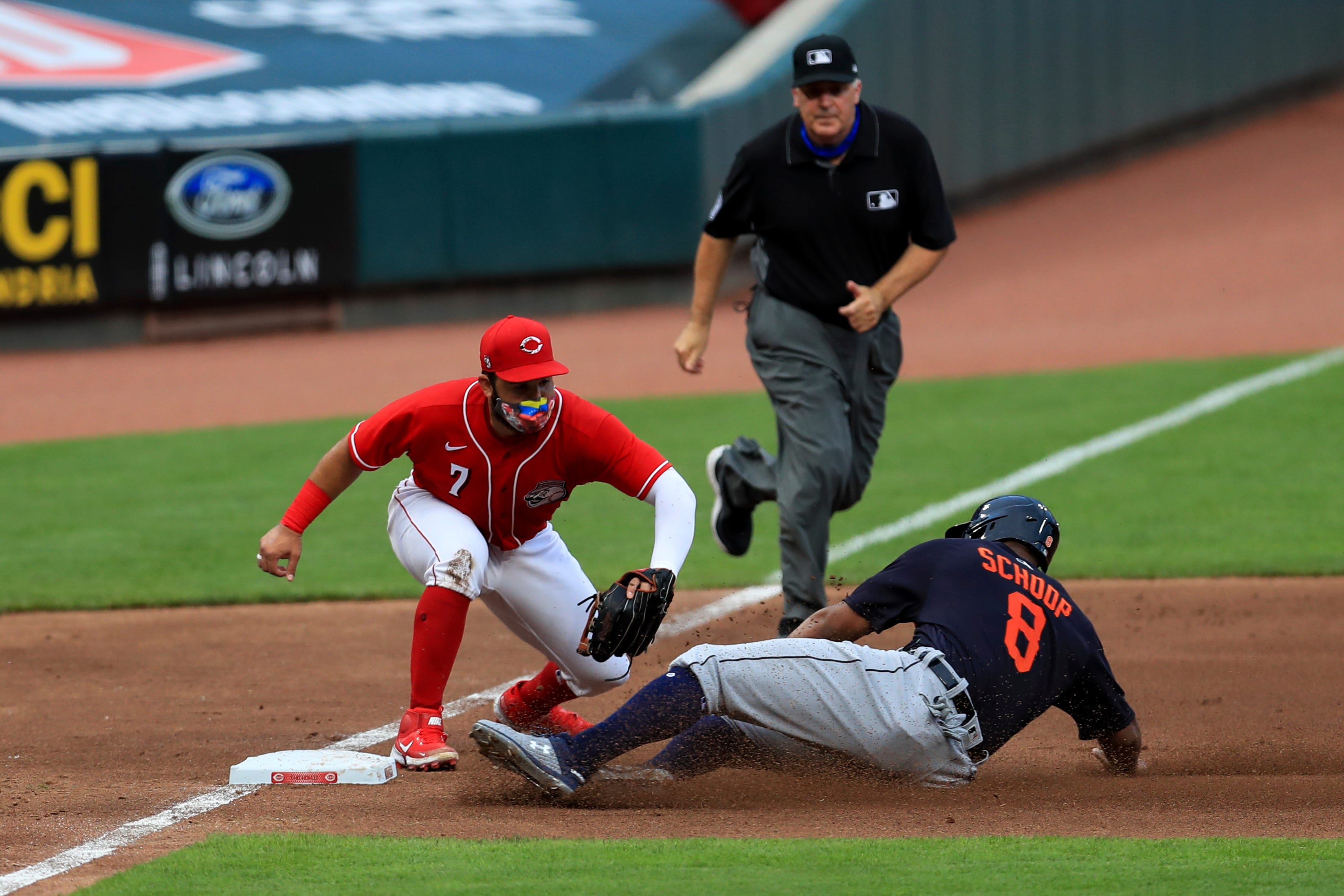 Cincinnati Reds third baseman Eugenio Suarez (7) tags out Detroit Tigers' Jonathan Schoop (8) during the fourth inning of an exhibition baseball game against the Detroit Tigers at Great American Ballpark in Cincinnati, on Tuesday, July 21, 2020.