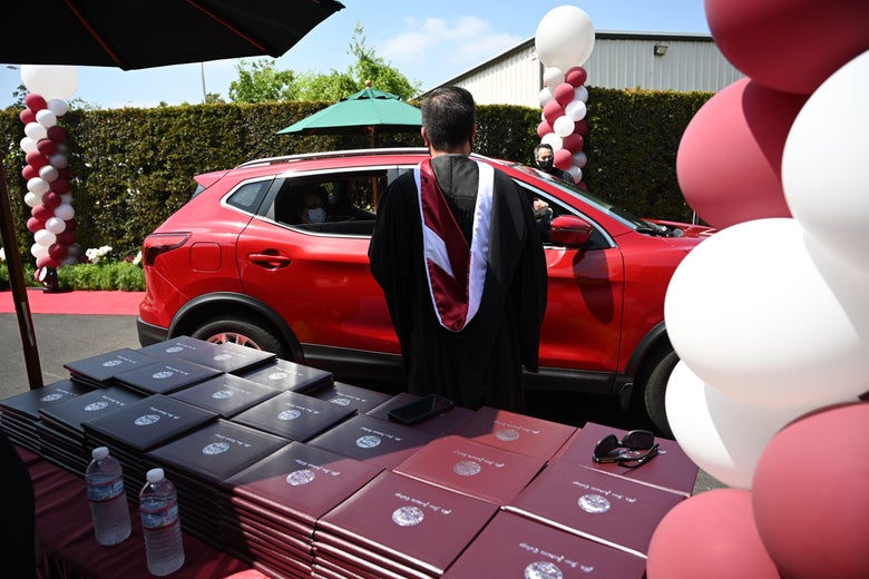 Graduating students receive their diplomas through a car window