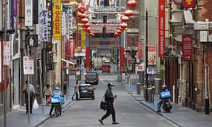 A man wearing a face mask crosses a quiet road in Melbourne’s Chinatown area.