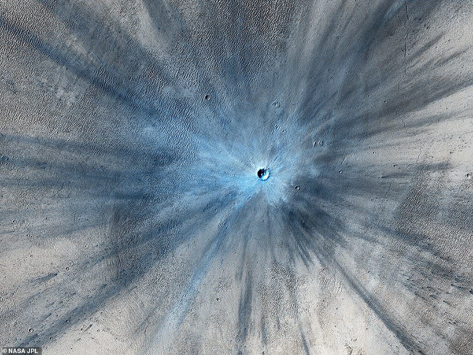A dramatic, fresh impact crater dominates this image taken by HiRISE. The crater spans approximately 100 feet (30 meters) in diameter and is surrounded by a large, rayed blast zone