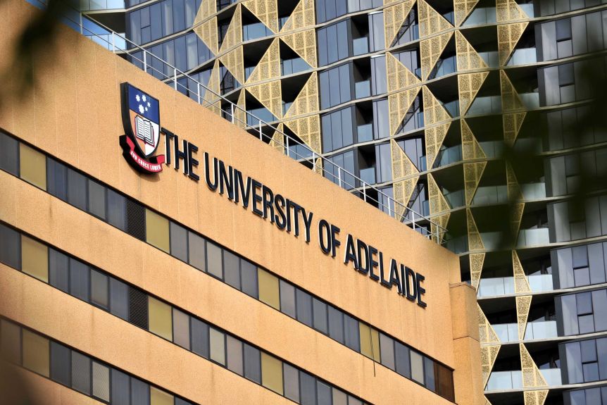 A building with a University of Adelaide sign on it with a taller one in the background