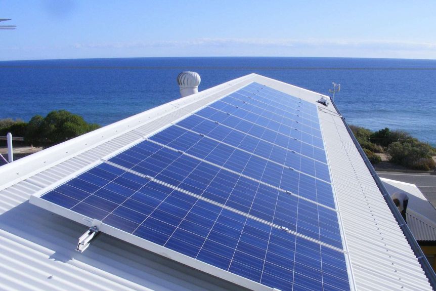 Solar panels on the white roof of a house by the ocean