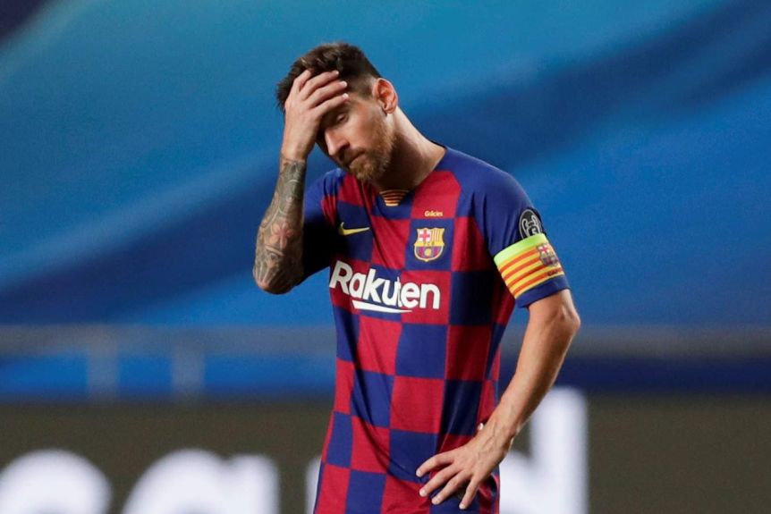 Lionel Messi holds his hand to his forehead as he stands on his own