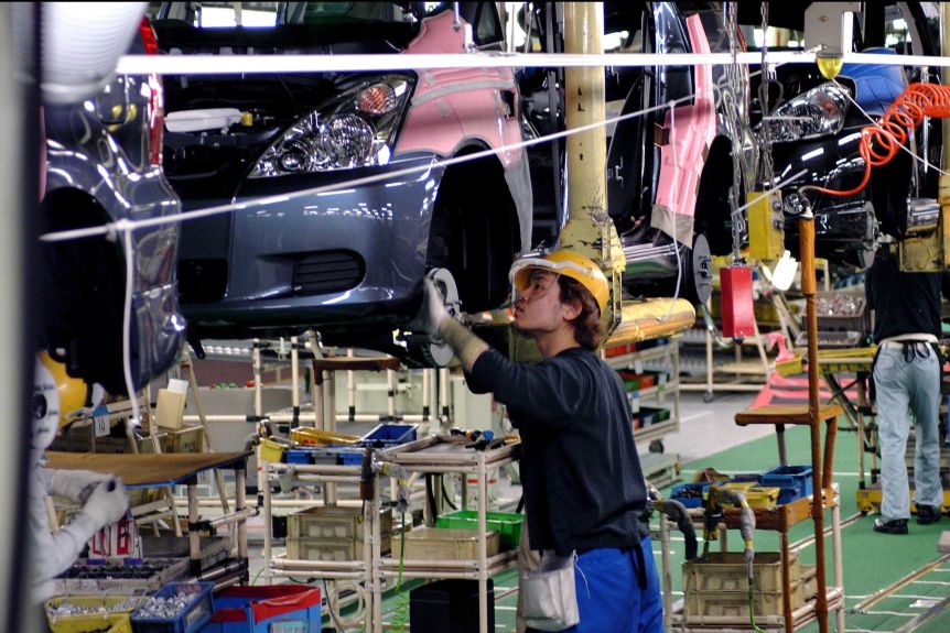 A man works on the Toyota motor plant assembly line.