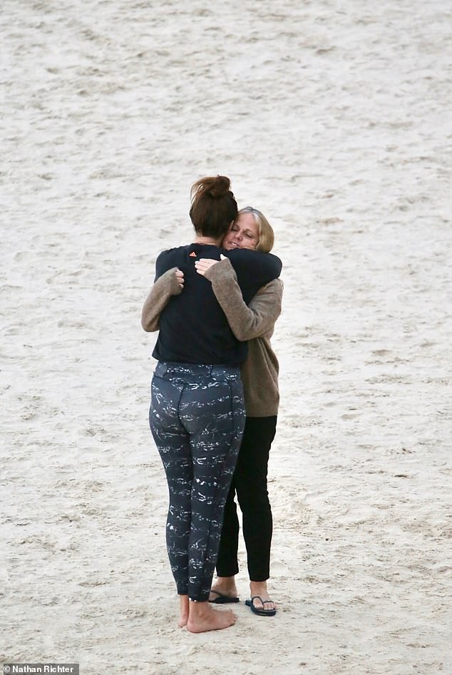 Two women embrace at Greenmount Beach Wednesday morning after the death of a surfer