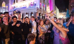 People sing and dance as they watch a street performer in Leicester Square.