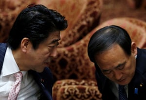 Japanese Prime Minister Shinzo Abe speaks to Prime Minister Yoshihide Suga at Parliament in Tokyo, February 2014.