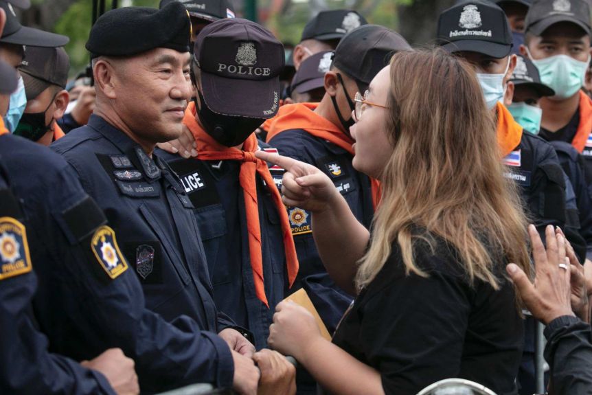 A young woman points her finger at a row of policemen 