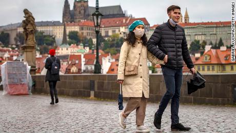 Tourists walk across the medieval Charles Bridge in Prague as the Czech Republic faces a record high after keeping numbers previously kept low.