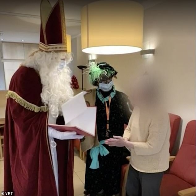Father Christmas talking to an elderly resident.  It appears that he and his assistant are standing more than two meters away from her