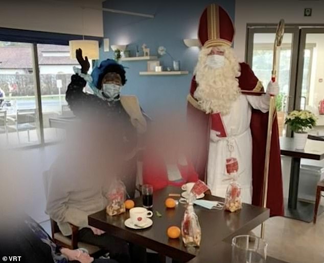 The volunteer dressed as a Sinterklaas was welcomed to spread Christmas cheer among the 150 residents of the Hemilrejk nursing home in Mall, Antwerp, last week (Pictured: Residents enjoy wine and oranges as Santa and his aides Zwarte Piet ('Black Pete') visiting the house)
