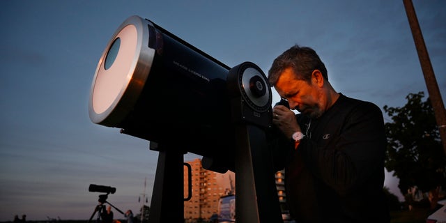 Robert Burgess, chief astronomer for southern Maine, sets up a telescope with solar filters to view a partial eclipse from the East Party in Portland on Thursday, June 10, 2021.