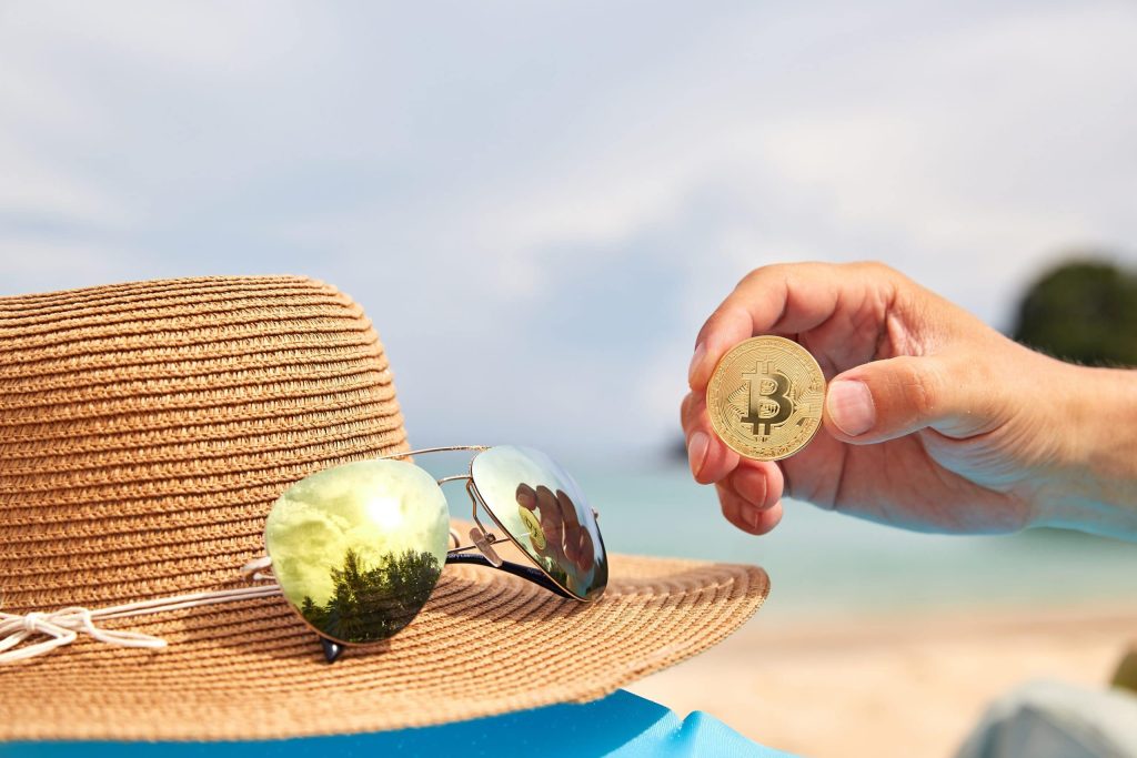 Bitcoin Münze neben Sonnenhut und Sonnenbrille